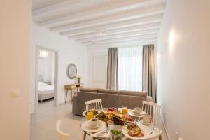 Vrisi/ MykonosDesire Mykonos Apartments的客厅配有沙发和餐桌,餐桌上摆放着食物