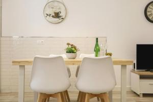 加的斯Apartamento Naypa with free parking的一张桌子、两把白色椅子和一瓶葡萄酒