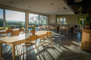 Hooglede布滕舒意斯住宿加早餐旅馆的餐厅设有木桌和椅子以及大窗户。