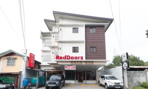 巴科洛德RedDoorz Plus @ Diola Villamonte Bacolod的一间红色门咖啡店,门前有汽车停放