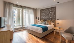 马德里Gran View Apartments的一间卧室配有一张床、一张书桌和一台电视。