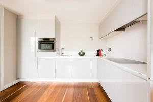 马德里Gran View Apartments的白色的厨房配有白色橱柜和木地板