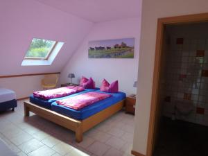 EltenHeidehof Pension B & B的一间卧室配有蓝色的床和粉红色枕头
