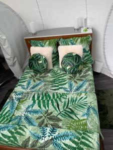 波尔兰特CHALET & MAISONS BULLES Deluxe的一张带绿色和白色毯子及枕头的床