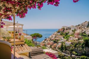 波西塔诺玛利亚别墅套房旅馆的从带粉红色花卉的山丘上欣赏波西塔诺(positano)的景色