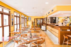 休达德亚Sagitario Hostal Ciutadella的拥有桌椅和黄色墙壁的餐厅
