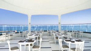 库萨达斯INFINITY BY YELKEN AQUAPARK&RESORTS KUŞADASI的餐厅设有白色的桌椅和窗户。