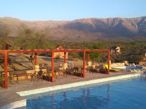诺诺Apart & Cabañas "Cañada del Sauce"的水边带桌椅的游泳池