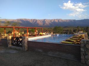 诺诺Apart & Cabañas "Cañada del Sauce"的一个带躺椅的游泳池,背景是山脉