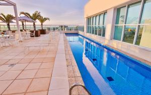巴西利亚圣莫里茨兰子快捷酒店的一座带桌椅的游泳池位于酒店大楼旁