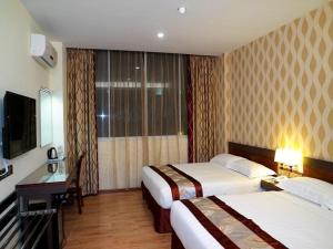 古晋Nova Kuching Hotel的酒店客房设有两张床和电视。