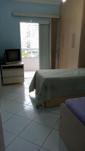 圣保罗Apartamento praia Grande的卧室配有1张床和1台电视,铺有瓷砖地板。