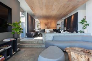 开普敦POD营地湾酒店的客厅设有蓝色的沙发和木制天花板
