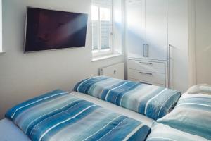 瓦尔内明德Ferienwohnung Windspiel的一间卧室配有两个蓝色枕头,墙上配有电视。