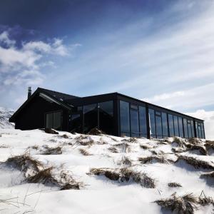 HofstaðirHofsstadir - Country Hotel的一座黑房子,位于一片白雪 ⁇ 的田野上,有一座建筑