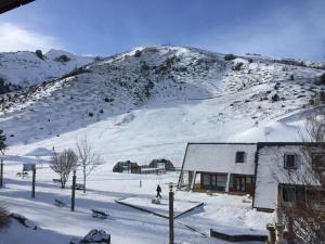Génos2 Appt 4 à 6 pers Val Louron au pied des pistes的雪地中的一座建筑,有雪覆盖的山