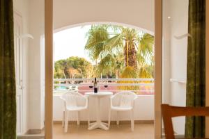 卡拉布兰卡Sagitario Vista Playa I Apartamentos的棕榈树间里的白色桌子和椅子