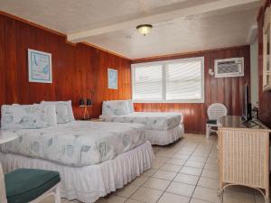 可可比奇Sea Aire Oceanfront Inn的一间带两张床铺的卧室,位于带木墙的房间内