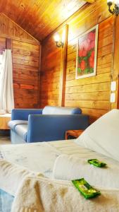 梅阿普格兰德港野营旅馆的一间设有两张床和椅子的客房,墙上挂有绘画作品