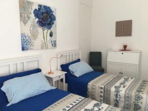 塔兰托Hibiscus的小客房内的两张床,配有蓝色的床单