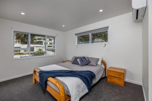 派西亚Waterfront Beach House - Paihia Holiday Home的一间卧室设有一张床和两个窗户。