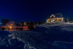 BańskaGóralska Dolina的夜晚雪中带圣诞灯的房子