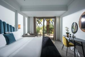 玛利亚Drossia Palms Hotel and Nisos Beach Suites的卧室配有一张白色大床和一张书桌