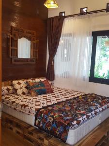 玛琅OMAH LUMUT Malang, Best Family Villa 3 Bedrooms Free Pool Kolam Renang的卧室内的一张大床,设有窗户