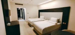 索哈尔Manazil Aldar Hotel的酒店客房设有两张床和窗户。