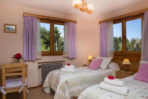 圣卡洛斯-德巴里洛切哈斯提莉亚凯蒂酒店的卧室内的两张床,配有紫色窗帘和窗户