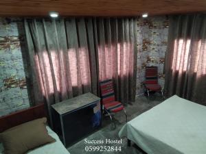 纳布卢斯Success Hostel的一间带床和两把椅子的房间以及一台电视