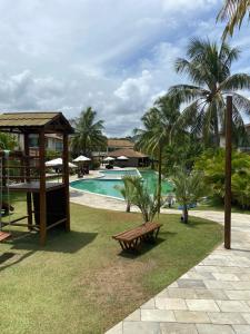 嘎林海斯港Muro alto Bangalô pé na areia的一个带游泳池、长凳和棕榈树的度假村