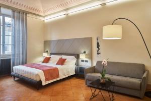 锡耶纳Residenza d'epoca San Martino 29的一间卧室配有一张床和一张沙发