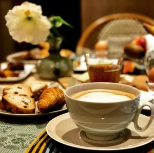 勒芒圣佛莱稣住宿加早餐旅馆的坐在桌子上边享用一杯咖啡和糕点