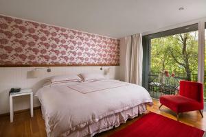 萨帕利亚尔卡萨萨帕拉尔酒店的一间卧室配有一张大床和一张红色椅子