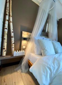 阿尔克马尔Casa De Palmas - Tiny house的卧室配有带白色枕头和树木的天蓬床。