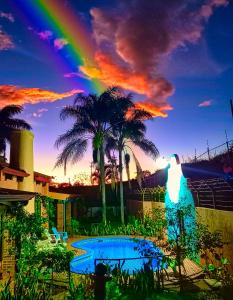 PotrerillosCasona del Valle的天空中的彩虹,带有游泳池和棕榈树