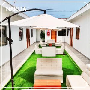 帕拉卡斯Nakua Paracas Lodge的庭院配有白色遮阳伞和绿色草地。