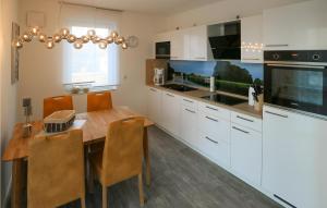 雷希林Beautiful Apartment In Rechlin With House Sea View的厨房配有白色橱柜和木桌