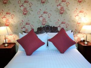 新港One Holyrood Hotel & Cafe的一间卧室配有一张带两个红色枕头的床
