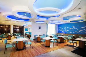 雅加达Grand Dafam Ancol Jakarta的餐厅设有桌椅和蓝色天花板。