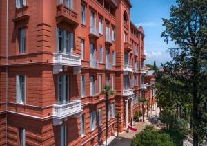 奥帕提亚Heritage Hotel Imperial - Liburnia的街道上带白色阳台的红砖建筑
