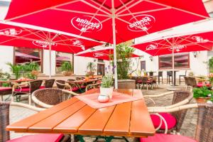 GroßenlüderHotel- Restaurant Zum Hirsch的餐厅里一张带红伞的木桌