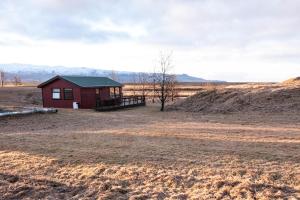 HellisholarSmáratún Cottages & Chalets的一座有树的田野上的红色小建筑