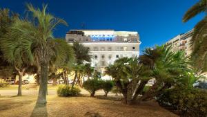 佩斯卡拉滨海酒店的一座白色的建筑,前面有棕榈树