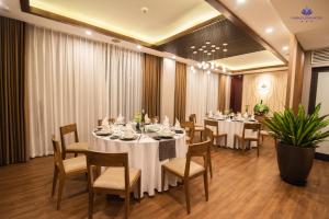 海阳Purple Lotus Hotel的一间设有白色桌椅的用餐室