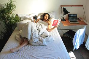 约翰内斯堡CURIOCITY Backpackers Johannesburg的躺在床上读书的女人