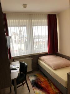 富尔达曼德法赫特皮特彻斯酒店的一间小卧室,配有一张床、一张书桌和窗户