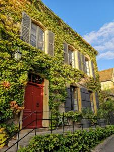 Bois-Sainte-MarieMaison d'hôtes - Les Tillets的一座常春藤覆盖的建筑,有红门