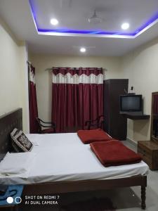 BalrāmpurHotel Avadh Balrampur的一间卧室配有一张床,并在一间客房内配有电视。
